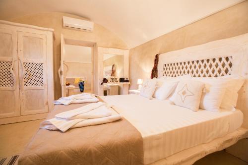 una camera da letto con un grande letto bianco con cuscini bianchi di LoveNest ad Akrotírion