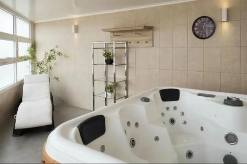 a large white bath tub in a room with a clock at Acogedor Dpto, Playa y Piscinas in La Serena
