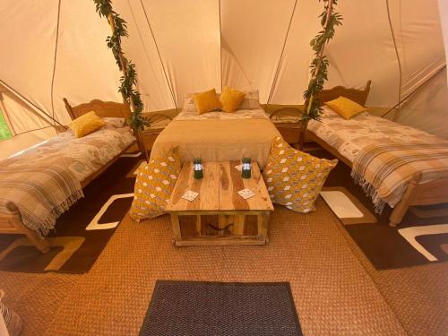 a room with two beds and a table in a tent at Hendre Glamping Retreat, The Rabbit Warren in Clydey