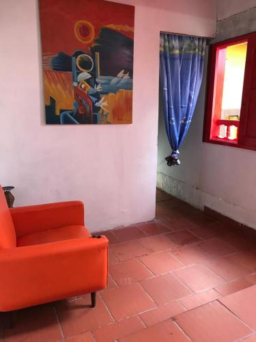 a living room with a red chair and a painting at Hostal Casa Ramirez in Jericó