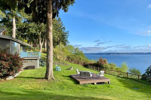 a table and chairs sitting on a lawn next to the water at Saratoga by the Sea by AvantStay Panoramic View Near Langley in Langley