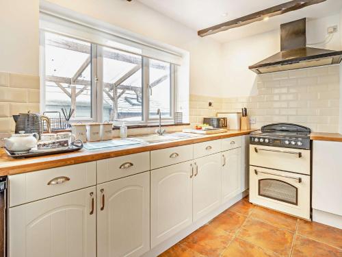 a kitchen with white cabinets and a window at 2 Bed in Oswestry 76537 in Gobowen