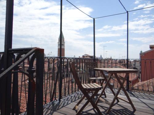 a table and chairs on a balcony with a clock tower at appartamento Casanova in Venice