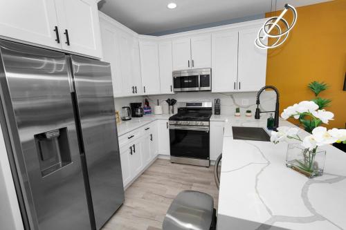 a kitchen with white cabinets and a stainless steel refrigerator at Spacious 3BR Family Oasis Sleeps 8 with Free Parking Near Medical District, Douglas Park and University of Illinois Chicago in Chicago