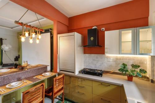 a kitchen with orange walls and a counter with chairs at Safari Homes by Secret TurtleProjectorSafariBBQ in Jigani