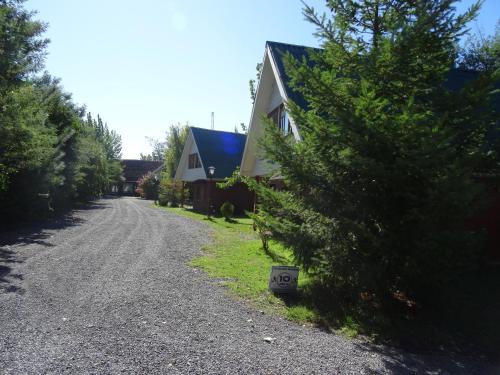 a gravel road next to a house with a tree at Cabañas Parque Salto del Laja in El Manzano