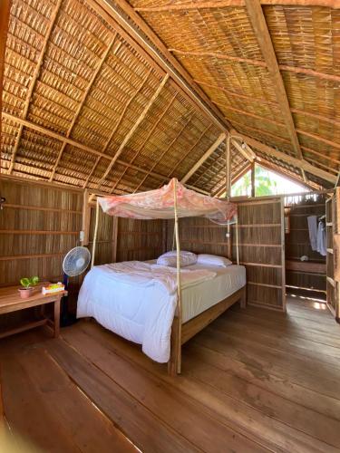 a bedroom with a bed in a straw roof at Fam Homestay in Fam