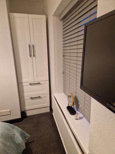 a bedroom with a tv and a white cabinet at The Church House Inn in Bollington