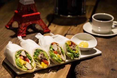 four sandwiches on a plate on a table with a cup of coffee at Hotel Les Champs Hualien in Hualien City