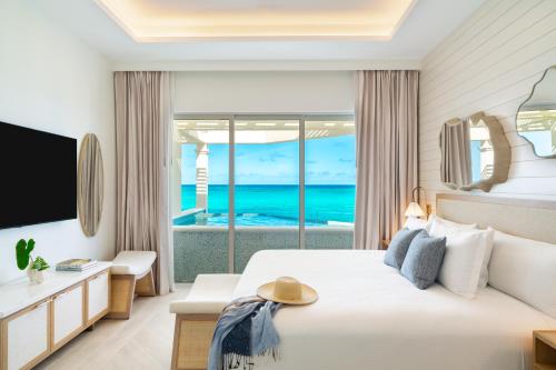 a hotel room with a bed and a view of the ocean at Windsong on the Reef in Grace Bay