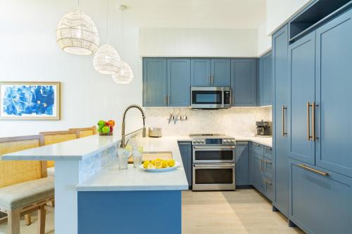 a kitchen with blue cabinets and a plate of fruit on a counter at Windsong on the Reef in Grace Bay