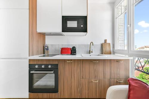 une cuisine avec une cuisinière et un micro-ondes dans l'établissement Magnifique appart rénové La Défense Paris Gare 2Pers, à Nanterre