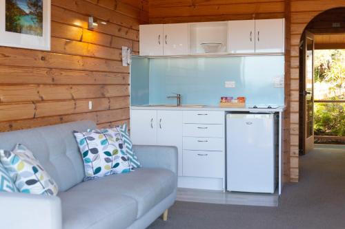 a living room with a couch and a kitchen at Kimi Ora Eco Resort in Kaiteriteri