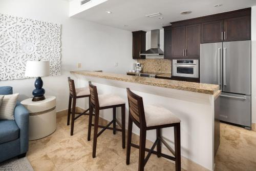 a kitchen with a bar with chairs and a couch at Windsong on the Reef in Grace Bay