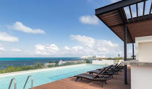 a pool with chairs and the ocean in the background at Beautiful sea view apartment in the Hotel Zone Cancun in Cancún