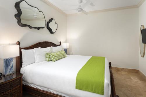 a bedroom with a bed with a green blanket on it at Windsong on the Reef in Grace Bay