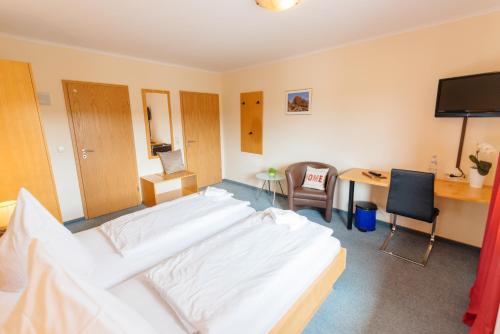 a hotel room with two beds and a desk and a television at Hotel Rhönhof in Hünfeld