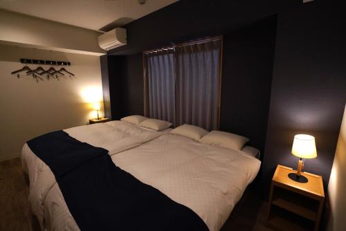 a bedroom with a large white bed with two lamps at GLANZ KEI Kyoto Station in Kyoto