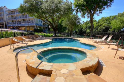 bañera de hidromasaje en un patio con sillas y un edificio en RRC A108 Grandmas River Haus, en New Braunfels