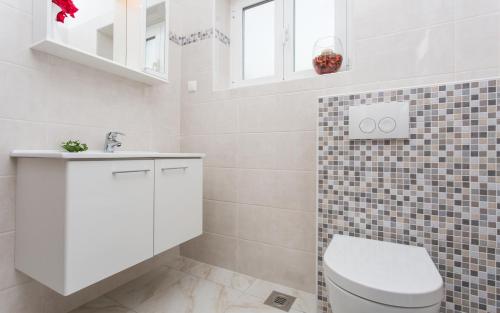 ein weißes Badezimmer mit Toilette und Waschbecken in der Unterkunft Apartments Lucija in Baška