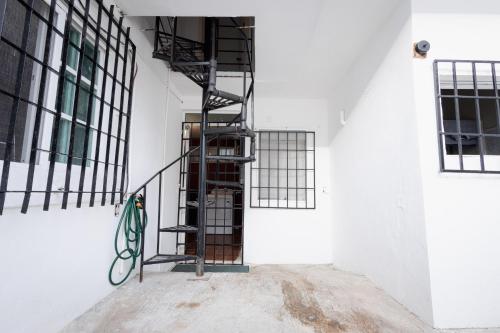 a black spiral staircase in a white wall with windows at Habitación compartida en el Centro de Cancún in Cancún