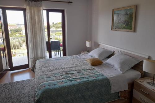 a bedroom with a bed with a view of a balcony at Apartments with parking space Banjol, Rab - 16334 in Rab
