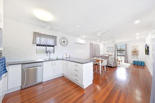 a kitchen with white cabinets and a wooden floor at Coastal Bliss at Kinka Beach! in Kinka