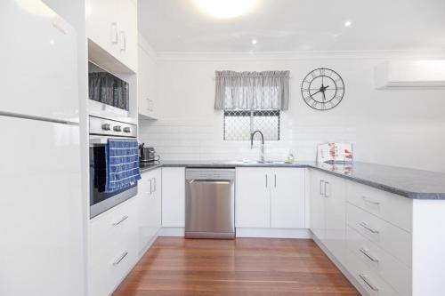 a white kitchen with white cabinets and a sink at Coastal Bliss at Kinka Beach! in Kinka