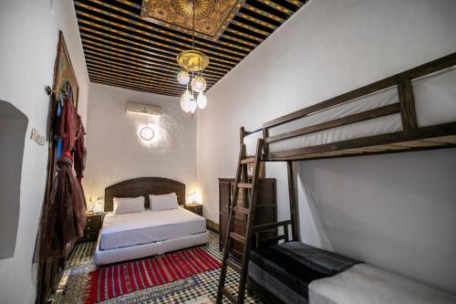1 dormitorio con 2 literas y lámpara de araña en Riad Fes Zyna, en Fez
