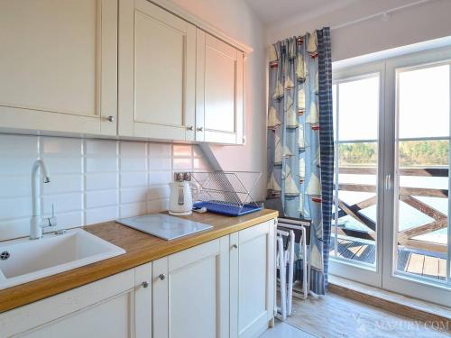 a kitchen with white cabinets and a sink and a window at Apartamenty i pokoje Mikołajki in Mikołajki