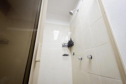 a bathroom with a shower and a white tile wall at Habitación compartida en el Centro de Cancún in Cancún
