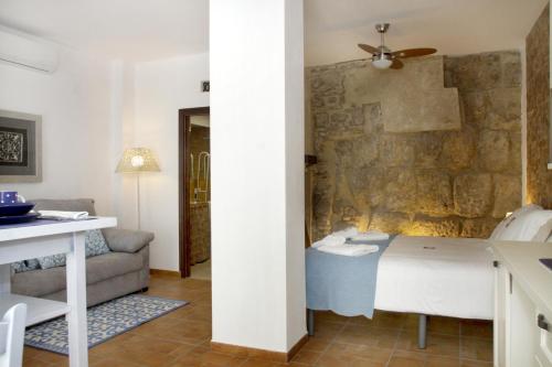une chambre avec un lit et un mur en pierre dans l'établissement Apartamentos San Fernando 76, à Cordoue