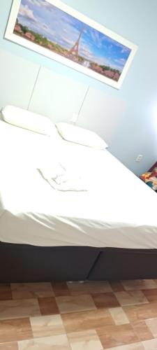 a white bed with a picture on top of it at Hotel Tabajara Apto 406 in Fortaleza