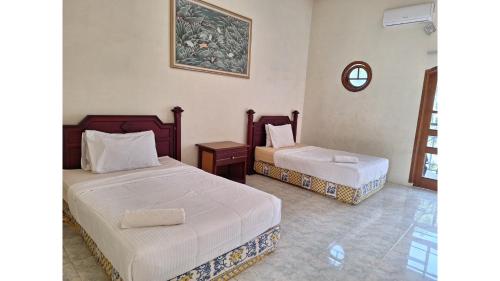 a bedroom with two beds and a clock on the wall at PLUM Hotel Palereman Batu in Batu