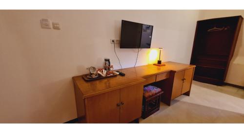 a room with a wooden desk with a television on it at PLUM Hotel Palereman Batu in Batu