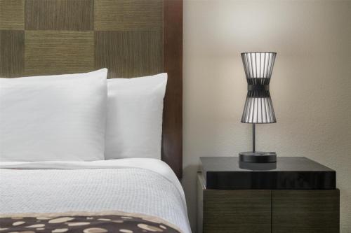 a bedroom with a bed and a lamp on a night stand at Best Western Premier Crown Chase Inn & Suites in Denton