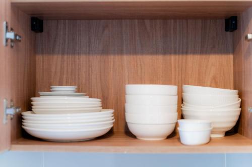 a group of white bowls and plates in a cabinet at Hua Hin La Casita Beautiful Two Bedroom Condo With Great Views in Hua Hin