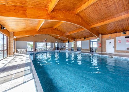a large indoor swimming pool with a wooden ceiling at Riverside Caravan Holiday Park in Bognor Regis