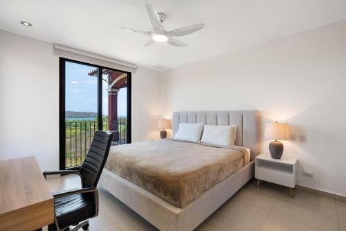 Un dormitorio con una cama y un escritorio y una ventana. en Bougainvillea 4315 Ph- Luxury 3 Bedroom Ocean View Resort Condo, en Brasilito