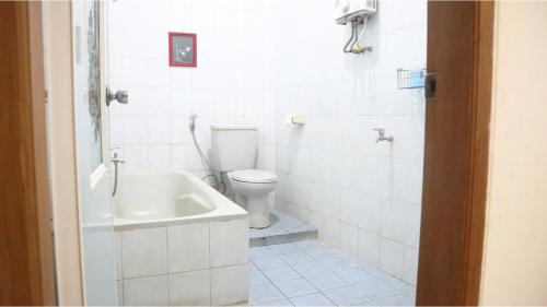 a white bathroom with a toilet and a sink at PLUM Hotel Palereman Batu in Batu