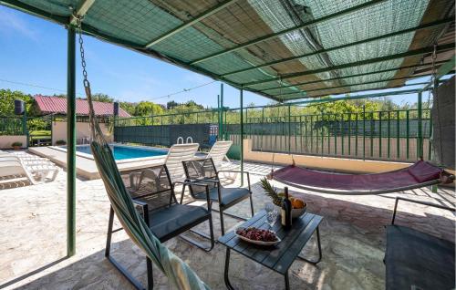 a patio with chairs and a hammock and a pool at Beautiful Apartment In Dubravice in Dubravice