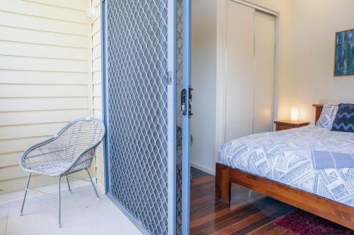 a bedroom with a bed and a chair next to a door at Halls Gap Escape Townhouses in Halls Gap
