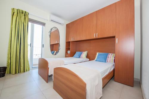 a hotel room with two beds and a mirror at The Waves Apartment Marsaxlokk in Marsaxlokk