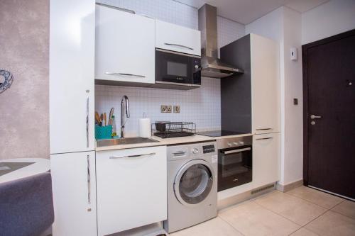 a kitchen with a washer and a white refrigerator at Descent Studio Apartment at Signature in Accra