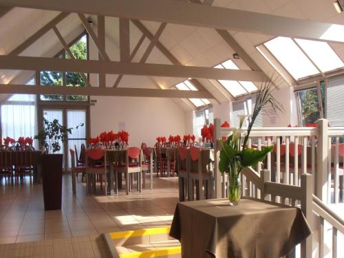 une pièce avec des tables et des chaises avec des fleurs rouges dans un vase dans l'établissement Gîte in Normandy near Sandy Beach, à Port-Bail-sur-Mer
