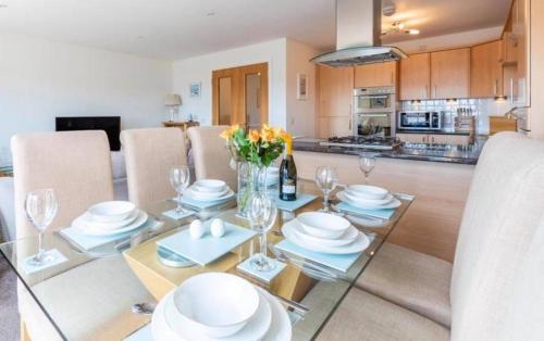 a dining room and kitchen with a table with plates and glasses at Coastal Haven- stunning home in Crail in Crail