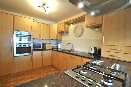 a kitchen with wooden cabinets and a stove top oven at Coastal Haven- stunning home in Crail in Crail