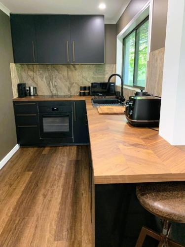 Una cocina con gabinetes negros y una encimera de madera. en The Pool House Carrara, en Gold Coast