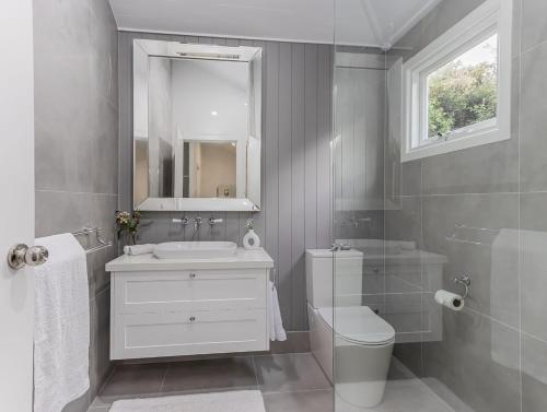 a bathroom with a sink and a toilet and a mirror at Hamptons White House in Murwillumbah