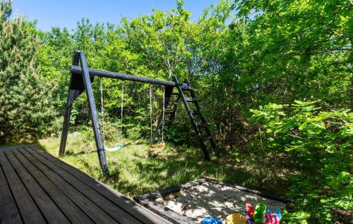 a swing on a wooden deck with trees at Cozy Home In Ringkøbing With Sauna in Ringkøbing